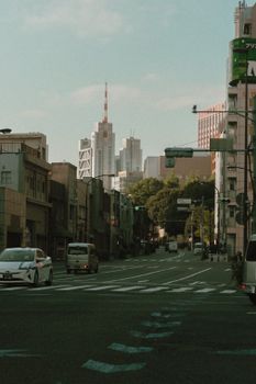 A vibrant city street in Tokyo with modern skyscrapers in the distance on a sunny day.