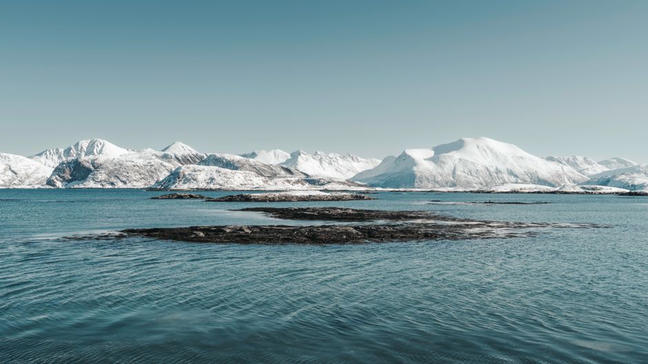 Breathtaking view of snow-capped mountains and calm waters in Arctic Norway.