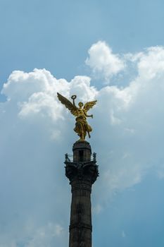 Golden Angel atop the Independence Monument in Mexico City against a blue sky.