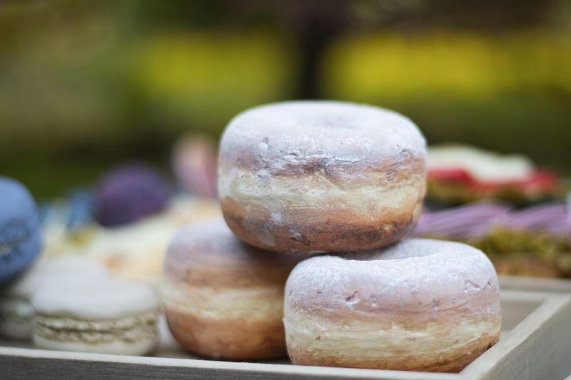 Powdered doughnuts stacked on a wooden tray, photo by Andrea Vámosné Kiss on Pexels