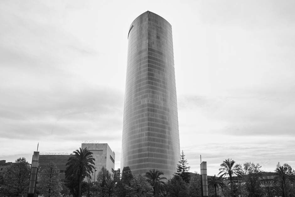 Rascacielos contemporáneo con palmeras en un paisaje urbano, en blanco y negro.