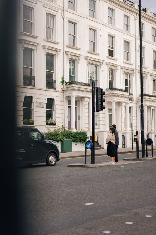 Free Woman waiting at crosswalk in London with classic Victorian buildings in background. Stock Photo