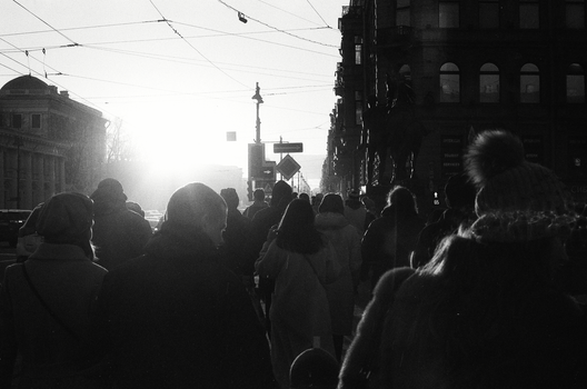 Silhouettes of people walking in a city street during sunrise with a vintage, moody tone.