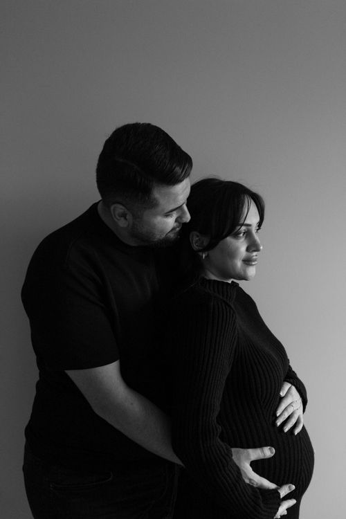 Free Intimate black and white portrait of expectant couple in warm embrace. Stock Photo