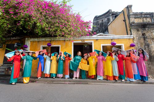 Free Vibrant group of women in Ao Dai in Hội An, Vietnam under bright bougainvillea. Stock Photo
