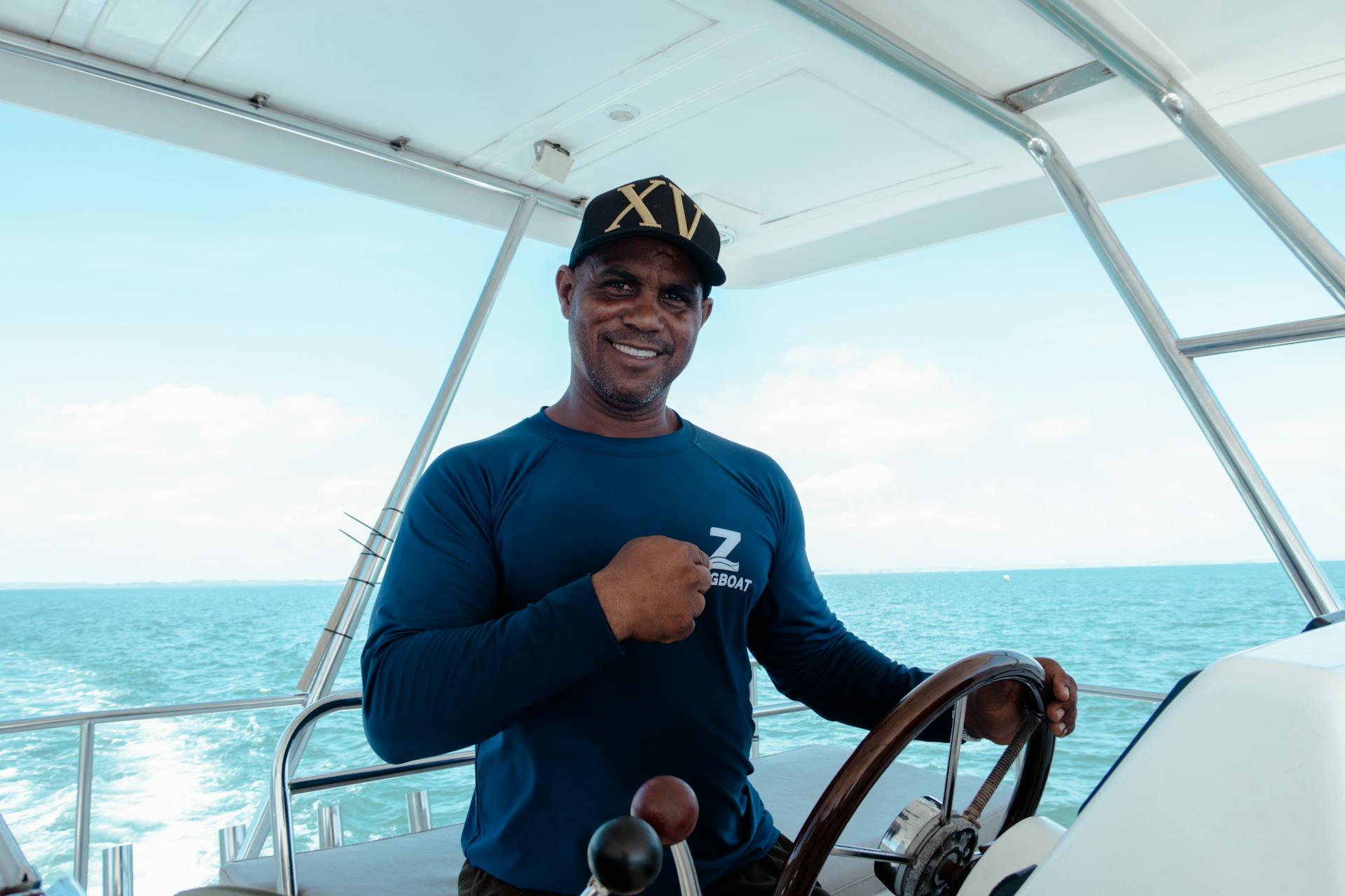 Portrait of a smiling boat captain steering in open waters under a clear sky.