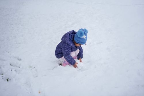 Free A young child in winter clothing plays in the snow, creating a joyful outdoor scene. Stock Photo