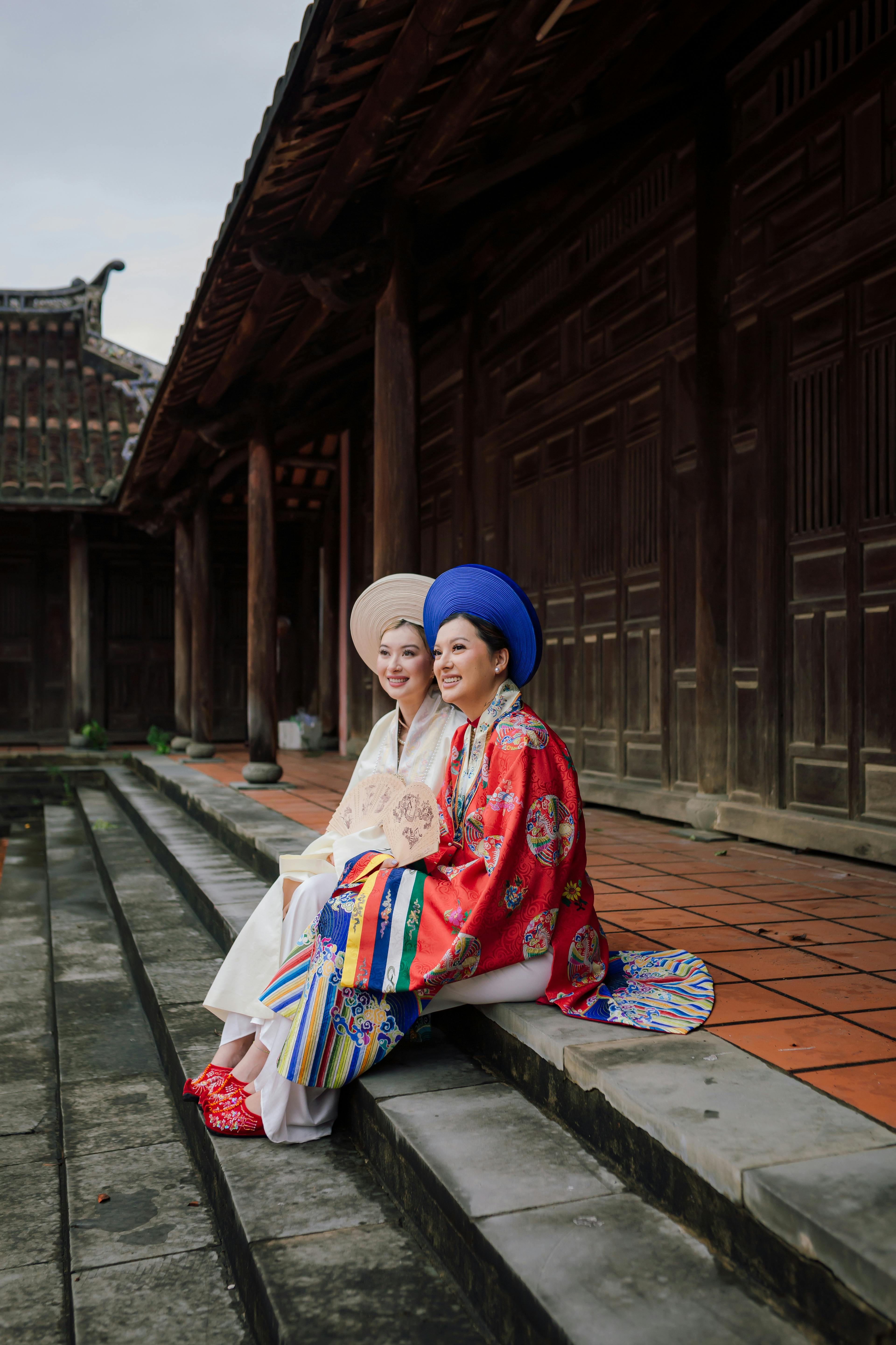 Women in traditional Vietnamese Áo Dài dresses at Hội An's historic temple.