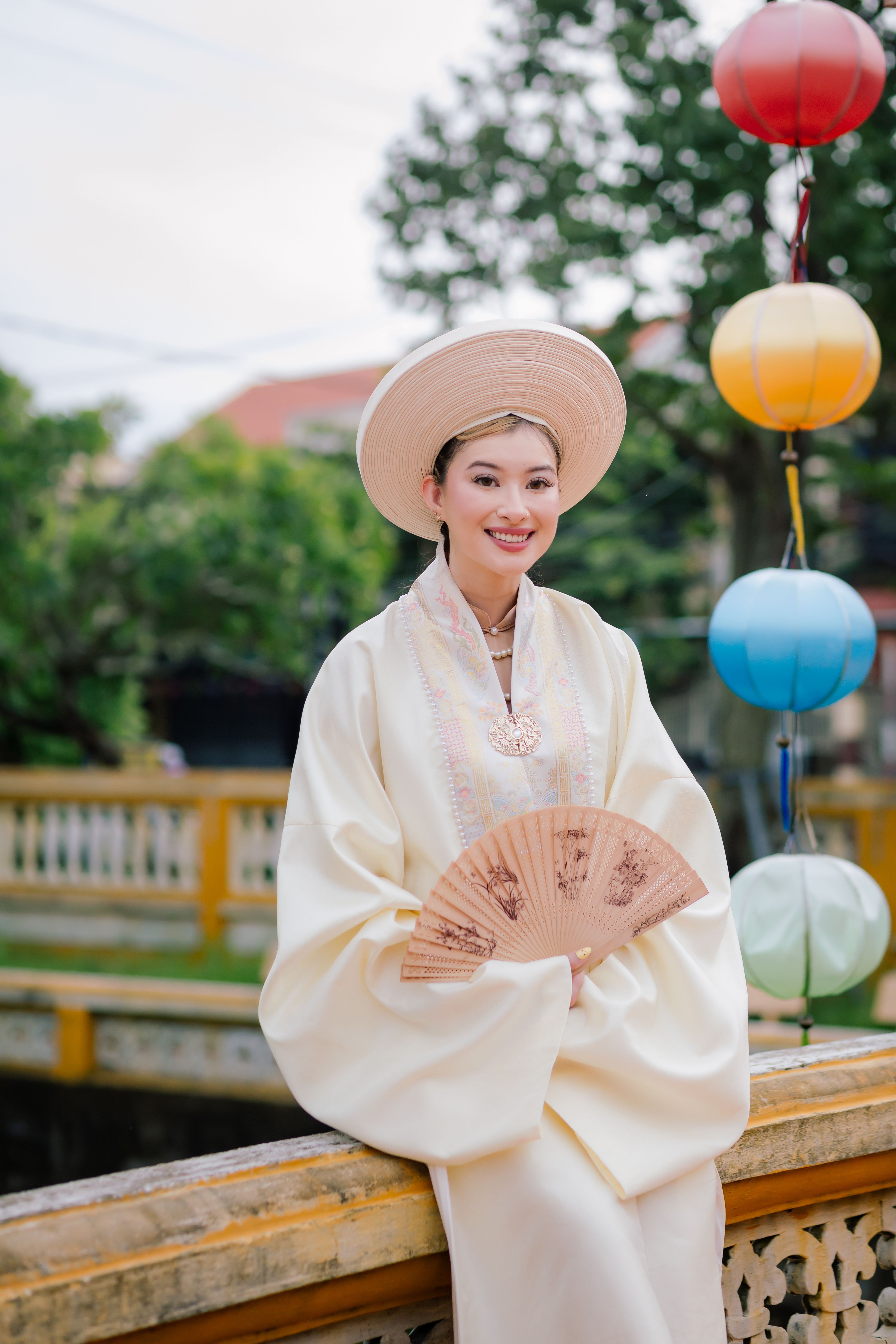 Woman in traditional Vietnamese attire sitting by lanterns in Hội An.