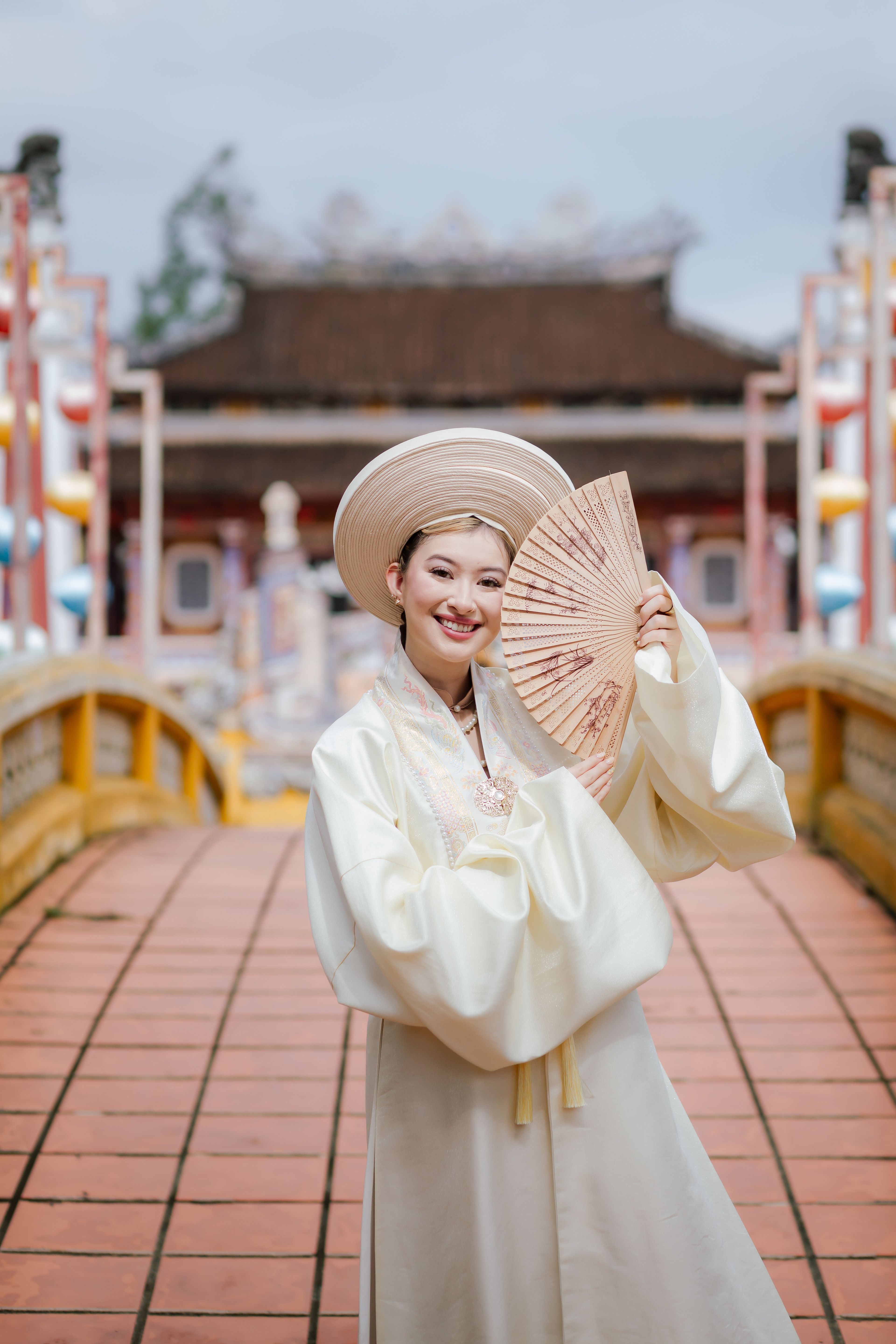 A woman in traditional Vietnamese attire poses on a bridge in Hoi An, capturing cultural elegance.