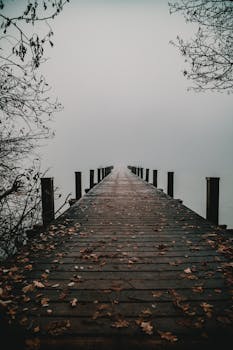 Misty wooden pier at Wörthsee, Bavaria creating a serene and chilly winter landscape.