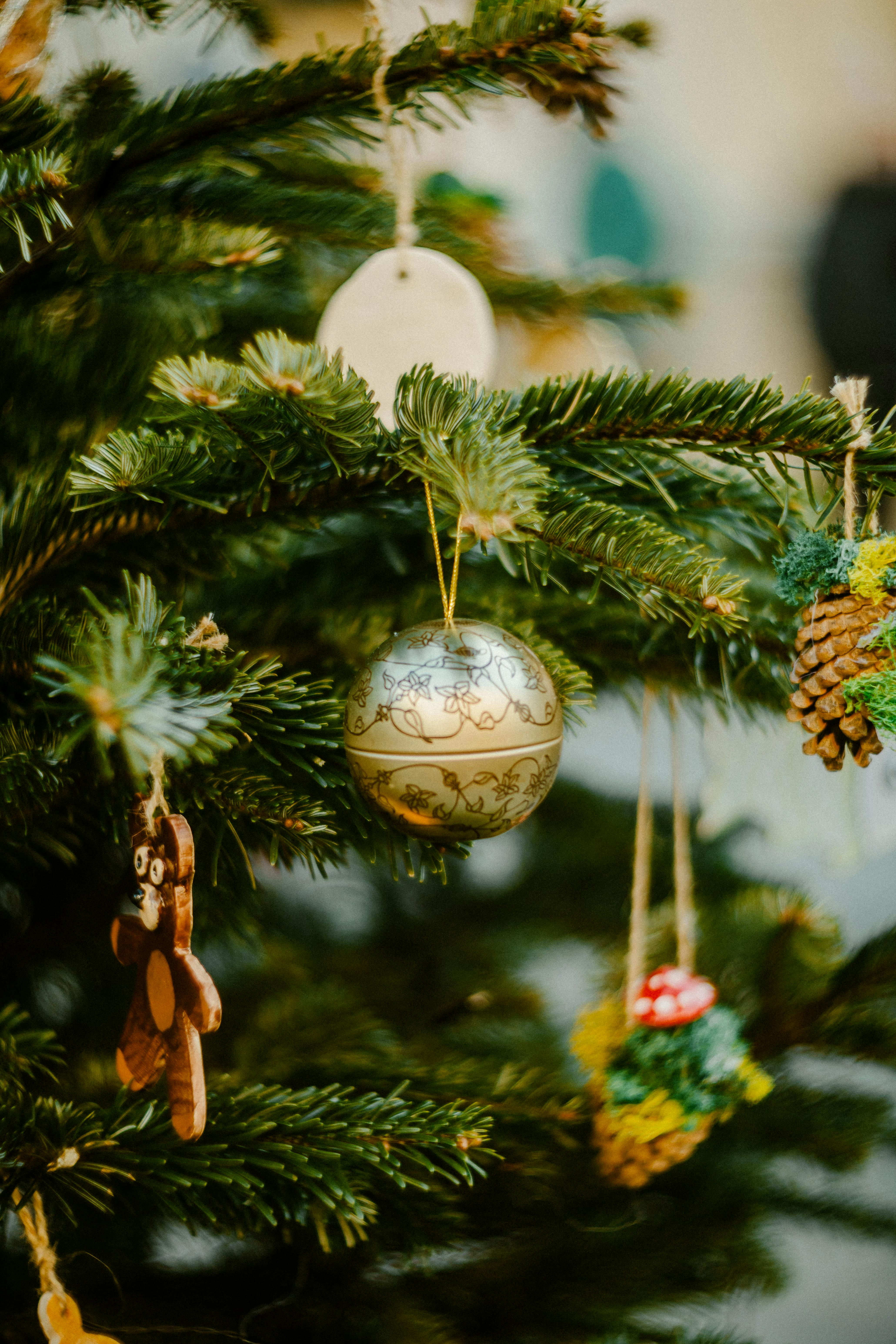 Close-up of a Christmas tree adorned with festive ornaments including a golden bauble.
