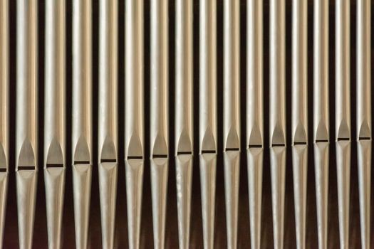 Symmetrical close-up of silver organ pipes in a row, showcasing musical symmetry.