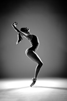 Graceful ballerina performing ballet leap. Artistic black and white image.