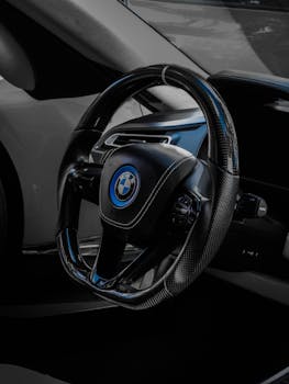 Close-up of a luxury car steering wheel showcasing sleek design and craftsmanship.