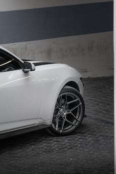 White Ford Mustang parked on a cobblestone street in an urban environment, showcasing luxury and performance.