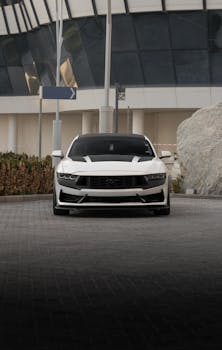 Sleek white Ford Mustang parked in a contemporary urban environment showcases luxury and power.