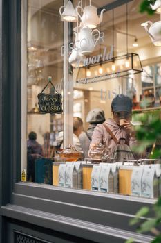 Window view of a cozy London tea shop showcasing teas and decor, capturing urban charm.