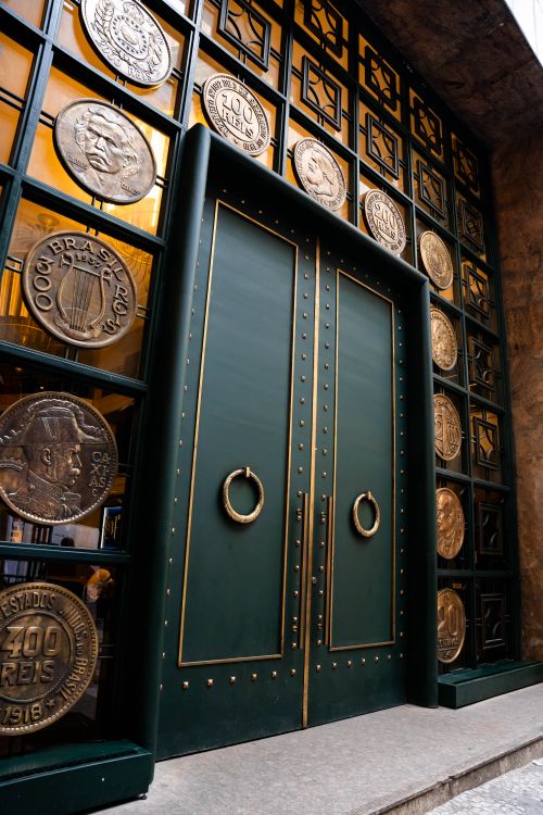 Free A stylish green doorway adorned with large bronze coin decorations in an urban setting. Stock Photo