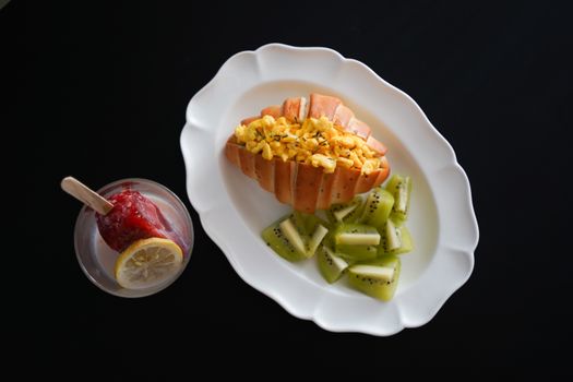 Delicious healthy breakfast with papaya, scrambled eggs, kiwi, and berry ice pop.