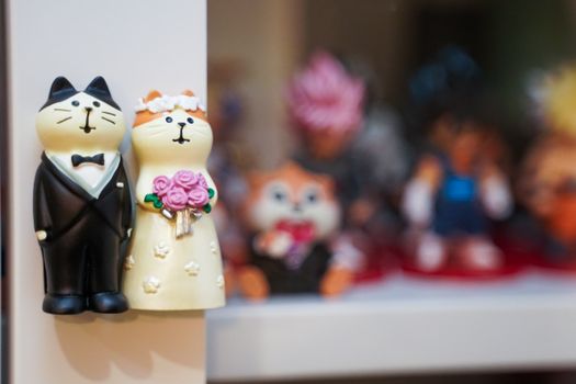 Charming cat couple wedding figurines showcased on a shelf with blurred background figurines.