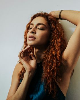 A serene portrait of a woman with red curly hair, eyes closed in tranquility.
