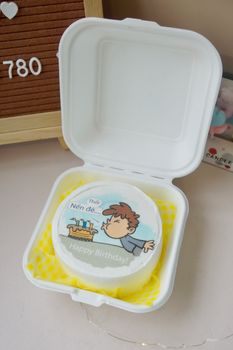 Decorative cartoon birthday cake in a takeaway box, perfect for celebrations.