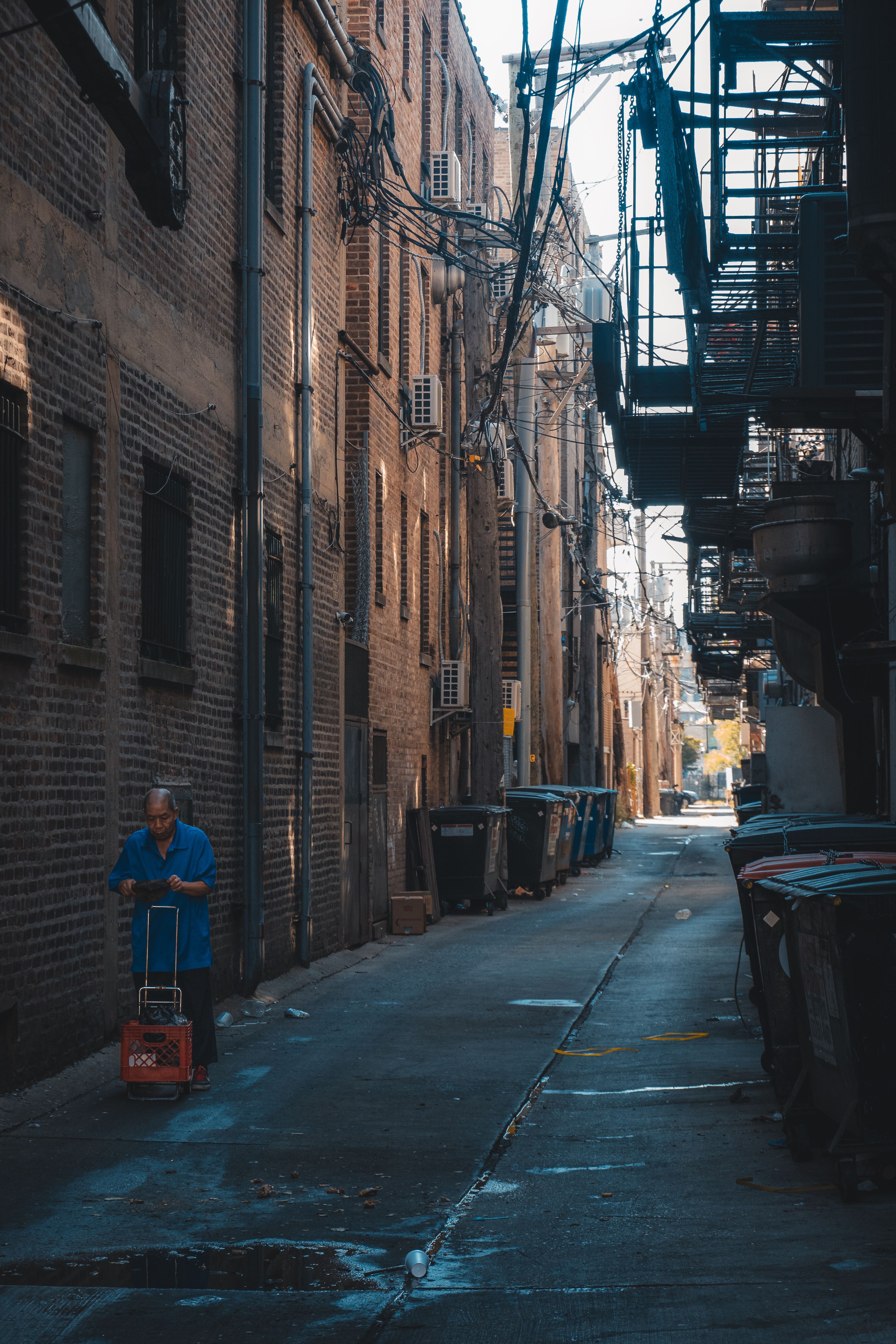 Urban alley with lone adult and towering buildings · Free Stock Photo