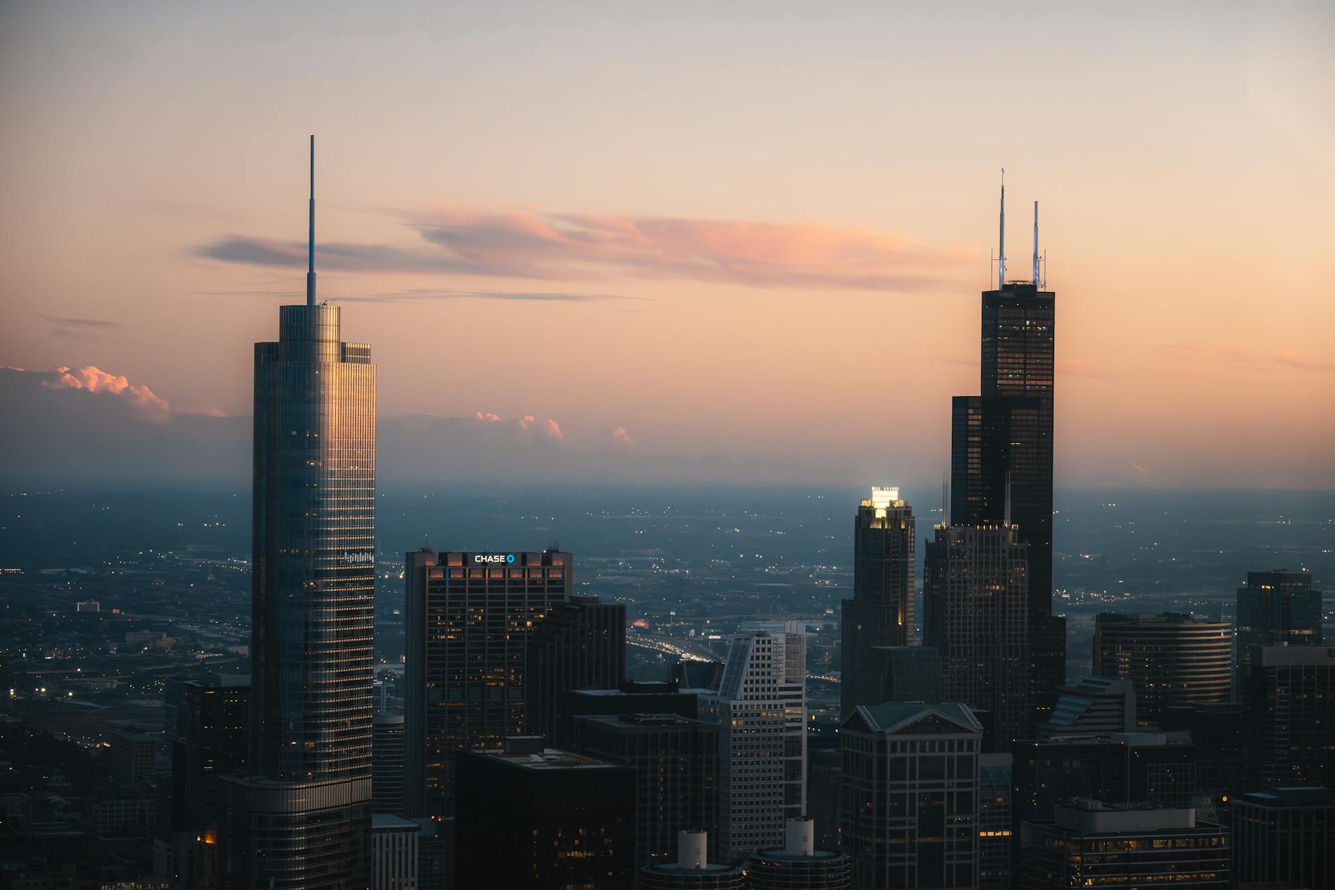 Chicago skyline featuring Willis Tower at sunset, showcasing urban skyscrapers under a colorful sky.