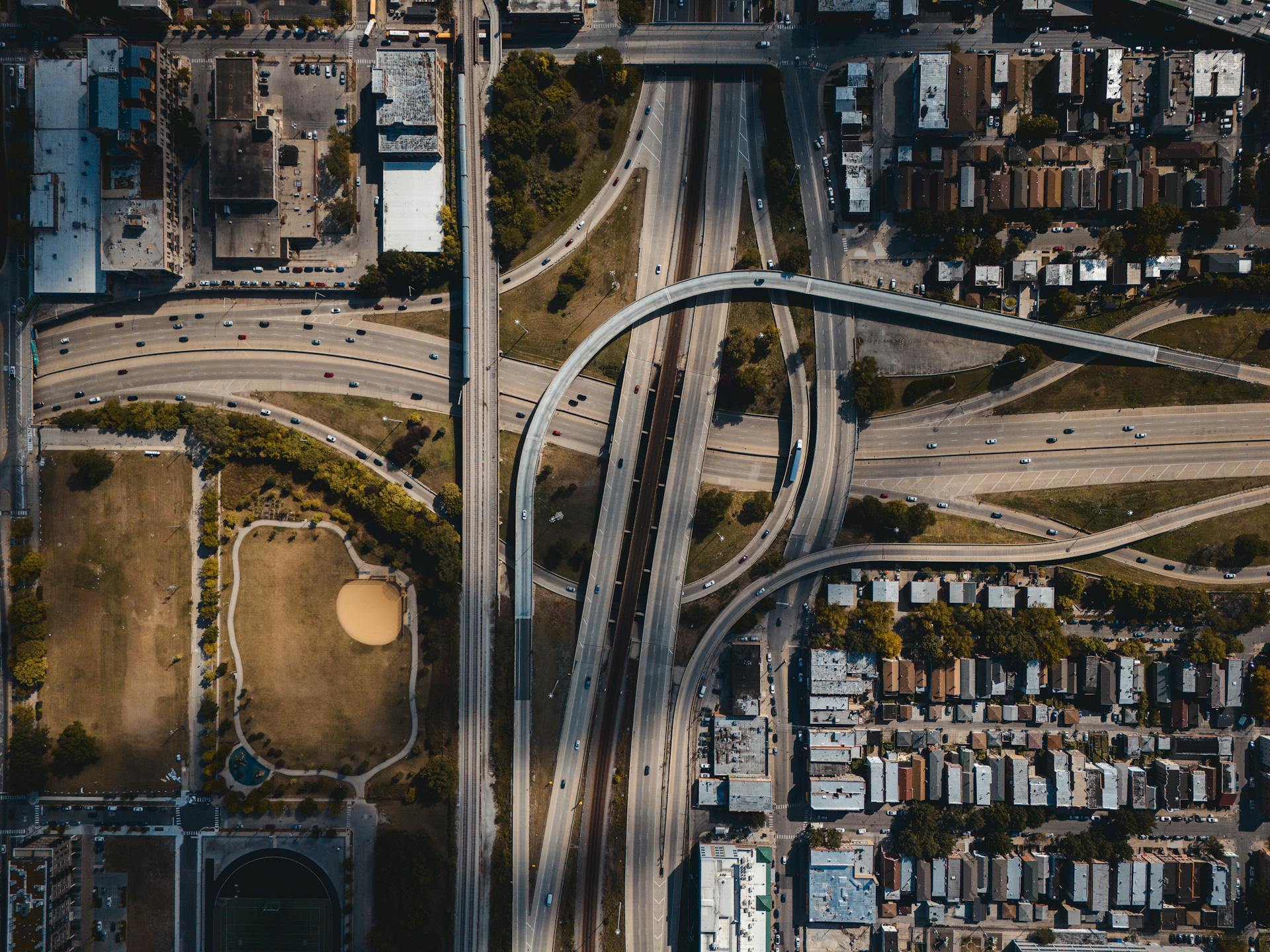 Aerial photo of a busy city highway interchange surrounded by buildings and greenery.