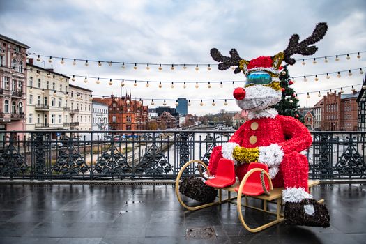 A decorative reindeer on a bridge with a cityscape backdrop, ideal for festive stock photography.