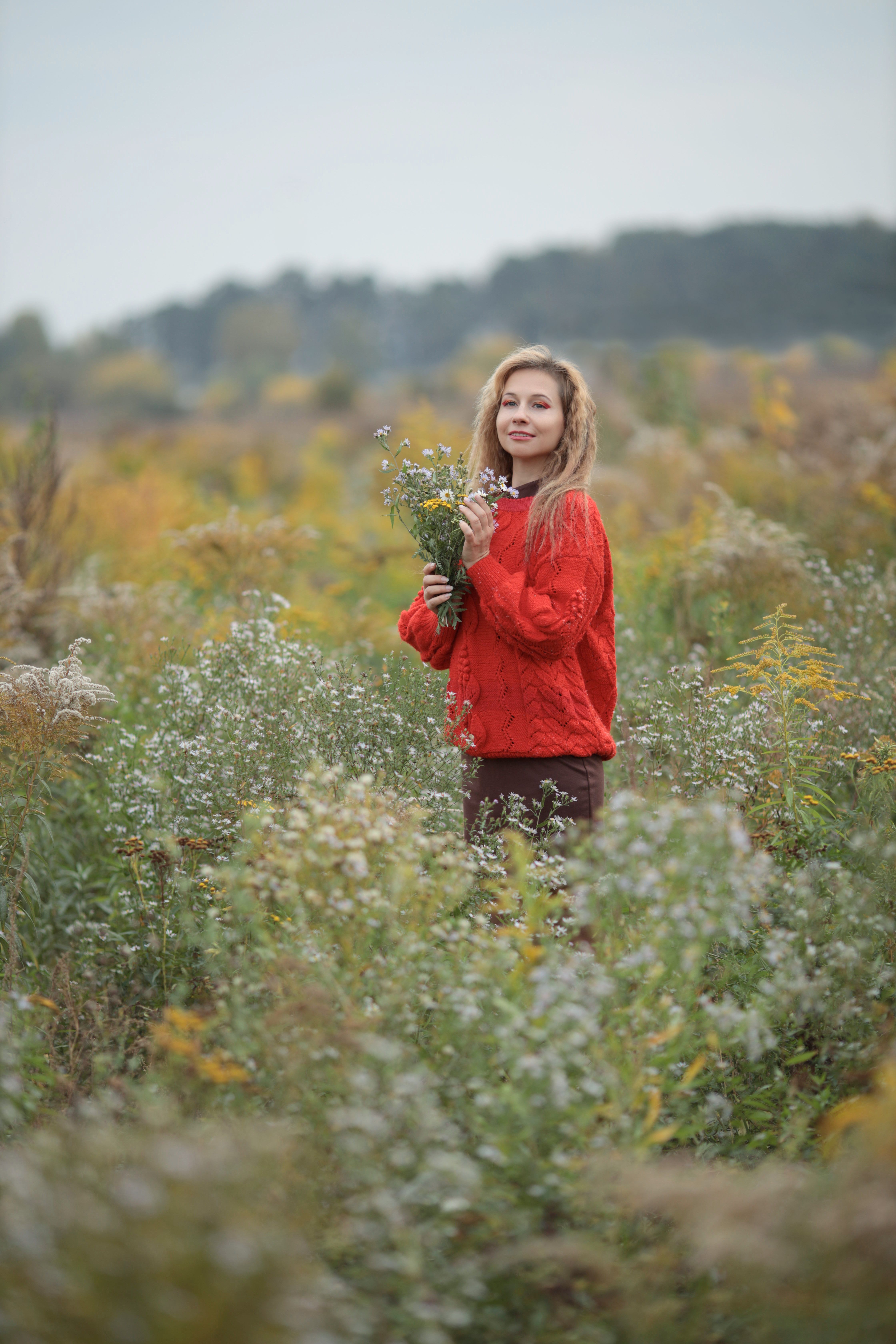 Woman in Red Sweater Holding Wildflowers Outdoors · Free Stock Photo