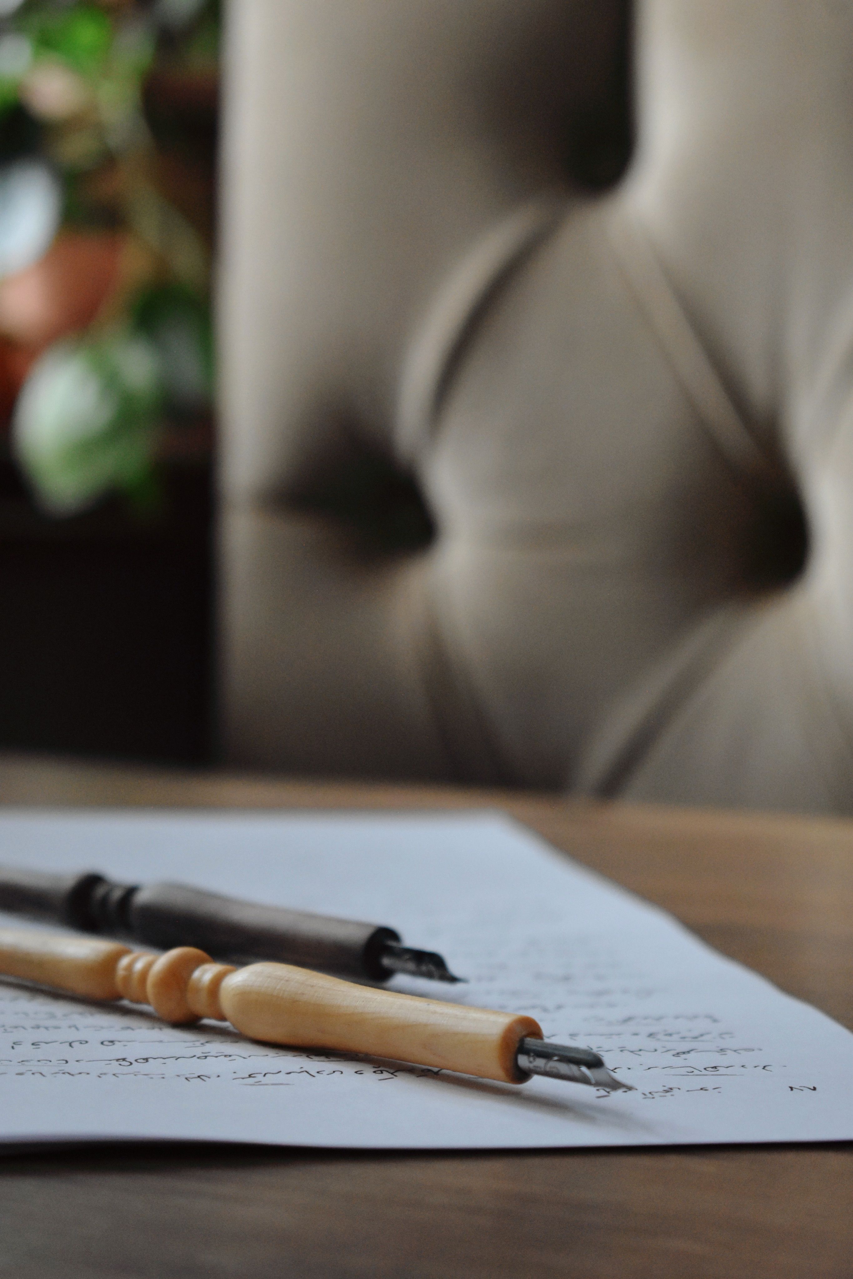 Artistic calligraphy pens rest on a handwritten page, evoking creativity.