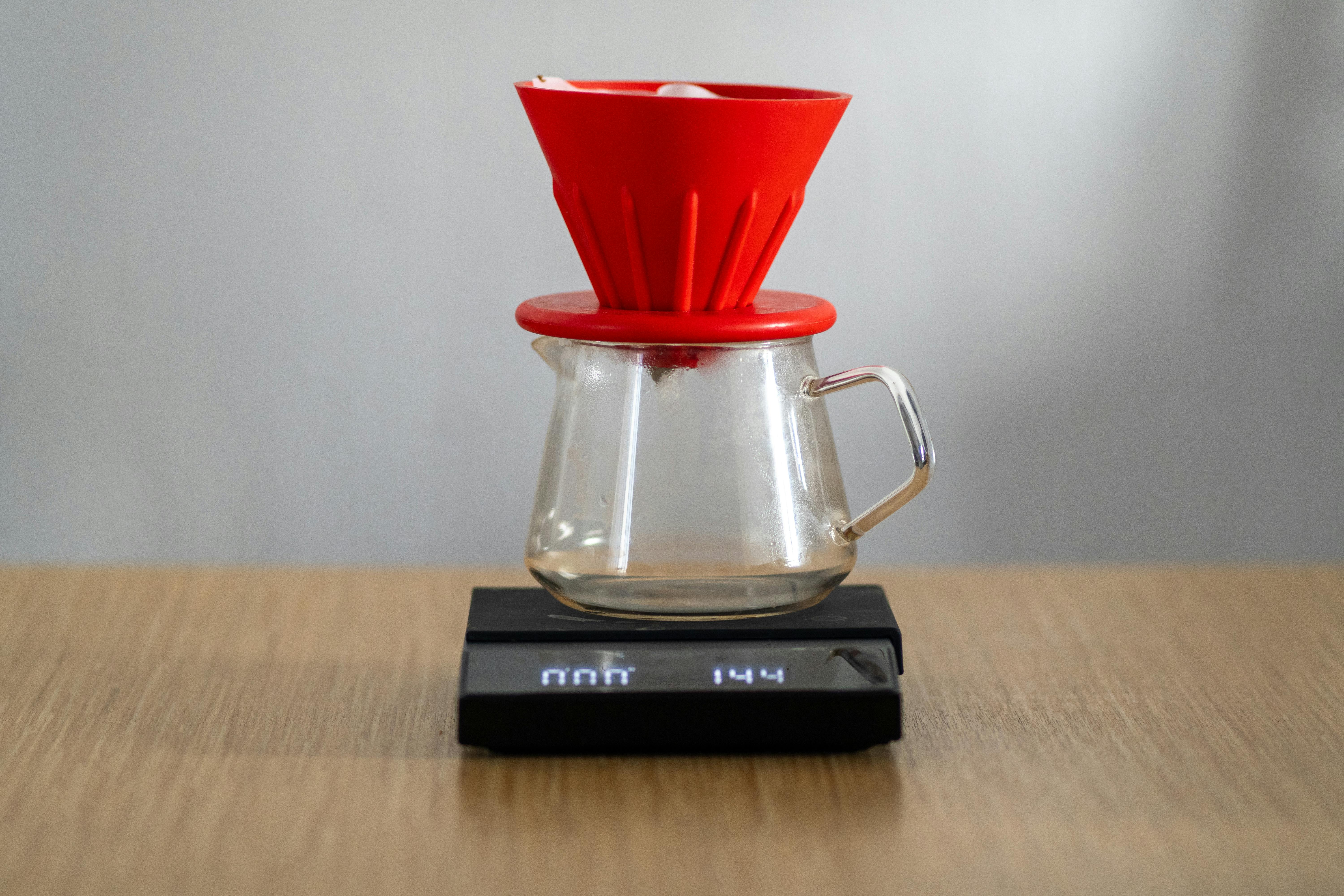 Red V60 coffee brewer on a digital scale, showcasing specialty coffee preparation.