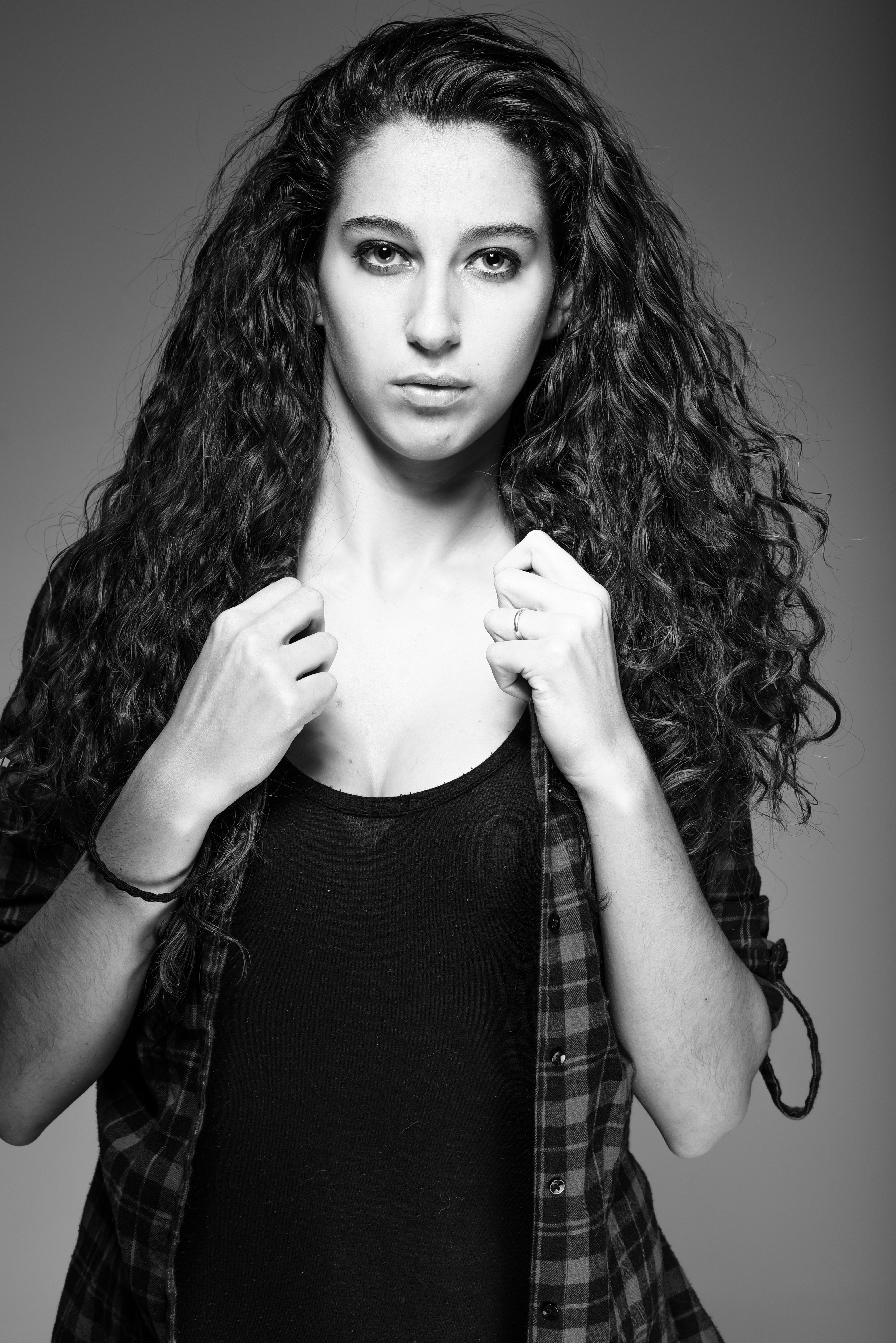 Striking black and white portrait of a woman with curly hair in a casual pose.