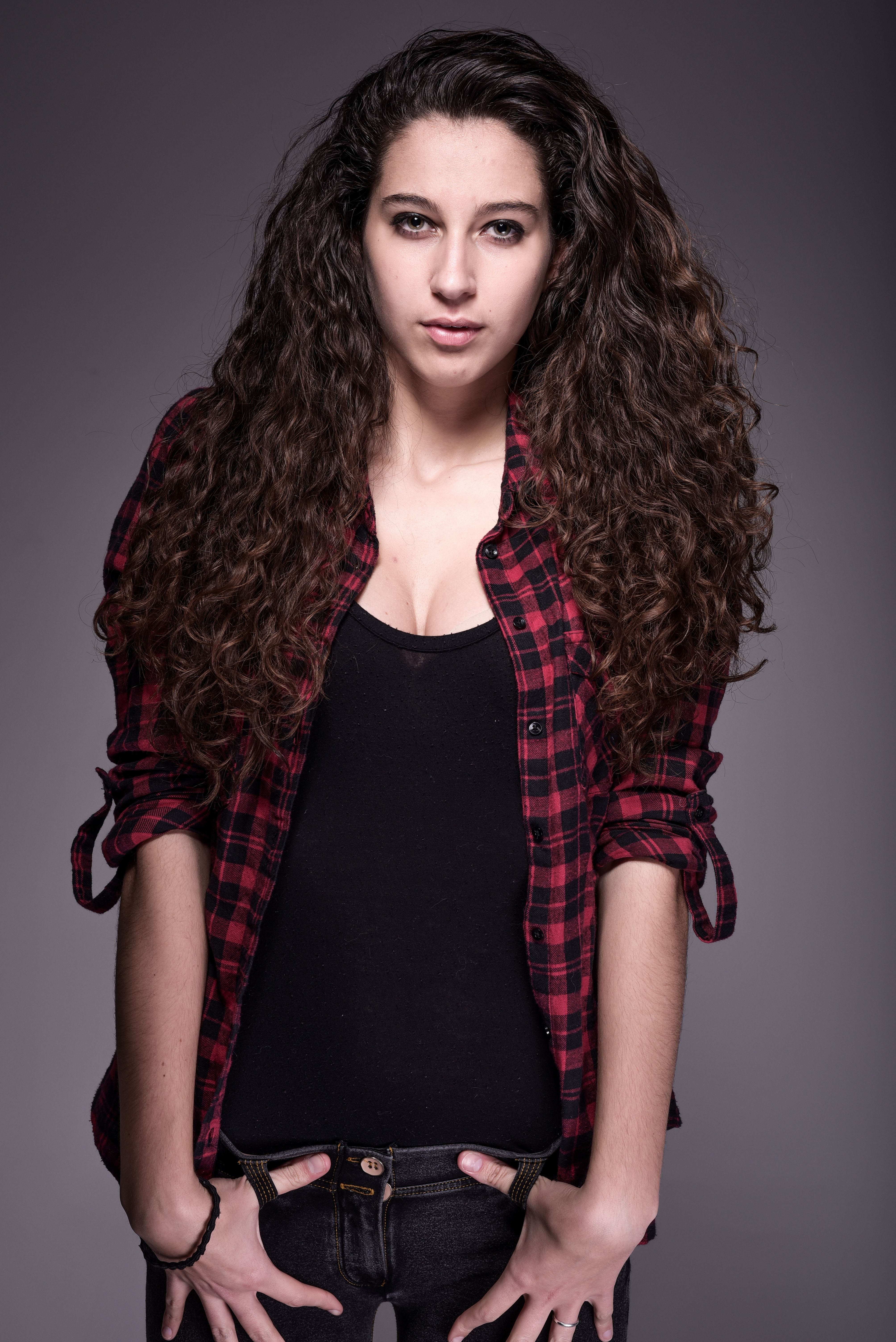 Portrait of a confident woman in casual attire with long curly hair.