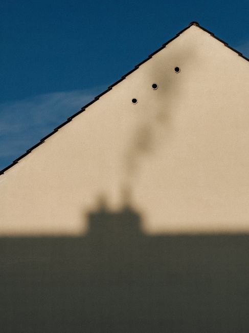 Minimalist photo of building shadow on gable wall with blue sky in Bayreuth, Germany.