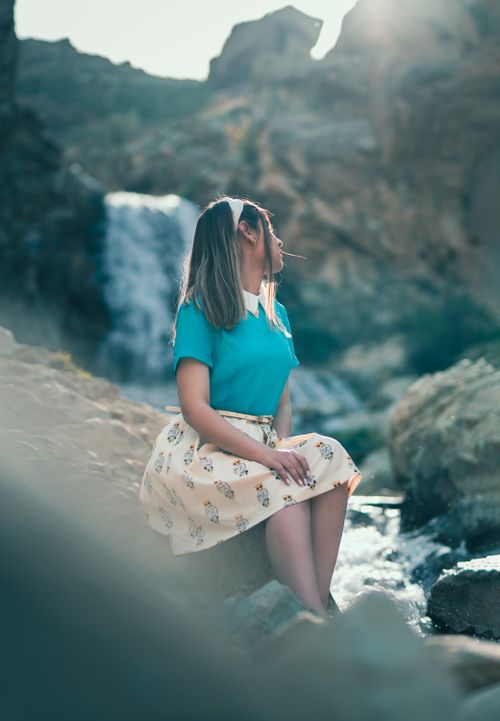 Free A young woman poses by a scenic waterfall, enjoying the serene outdoors. Stock Photo