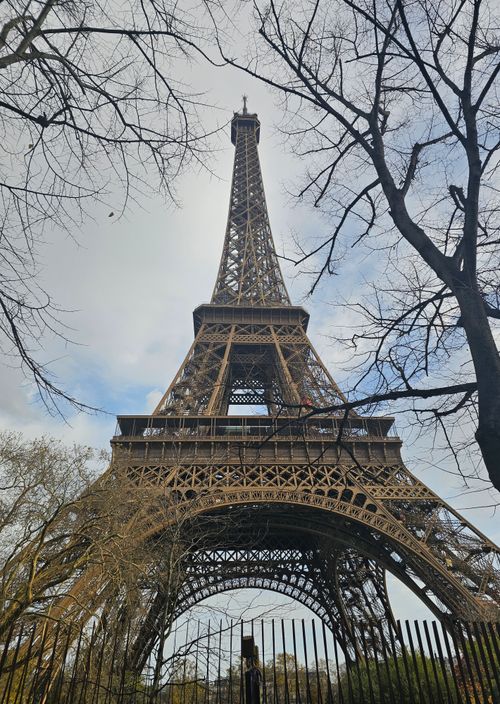 Free A captivating view of the Eiffel Tower against a partly cloudy sky, capturing the essence of spring in Paris. Stock Photo