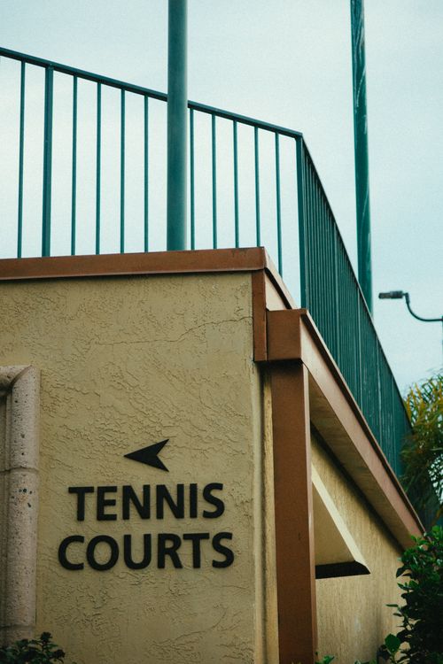 Free Entrance to a tennis court featuring a modern wall design with metal railing. Stock Photo