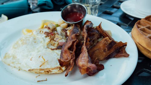 Lanières De Bacon Et Plat D'oeufs Sunny Side Up Sur Plaque Ronde En Céramique Blanche