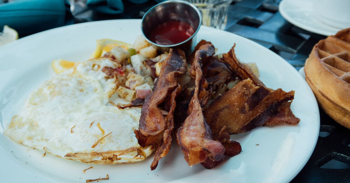 plate of scrambled eggs with bacon and butter