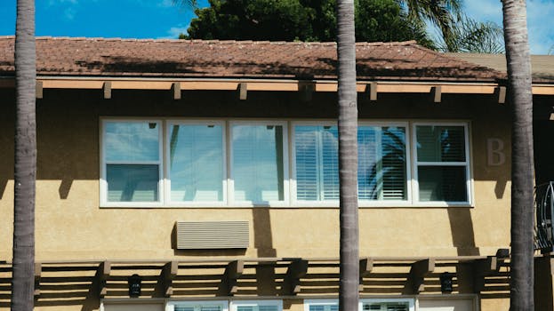 现代住宅楼立面前种植着棕榈树，映衬着清澈的蓝天