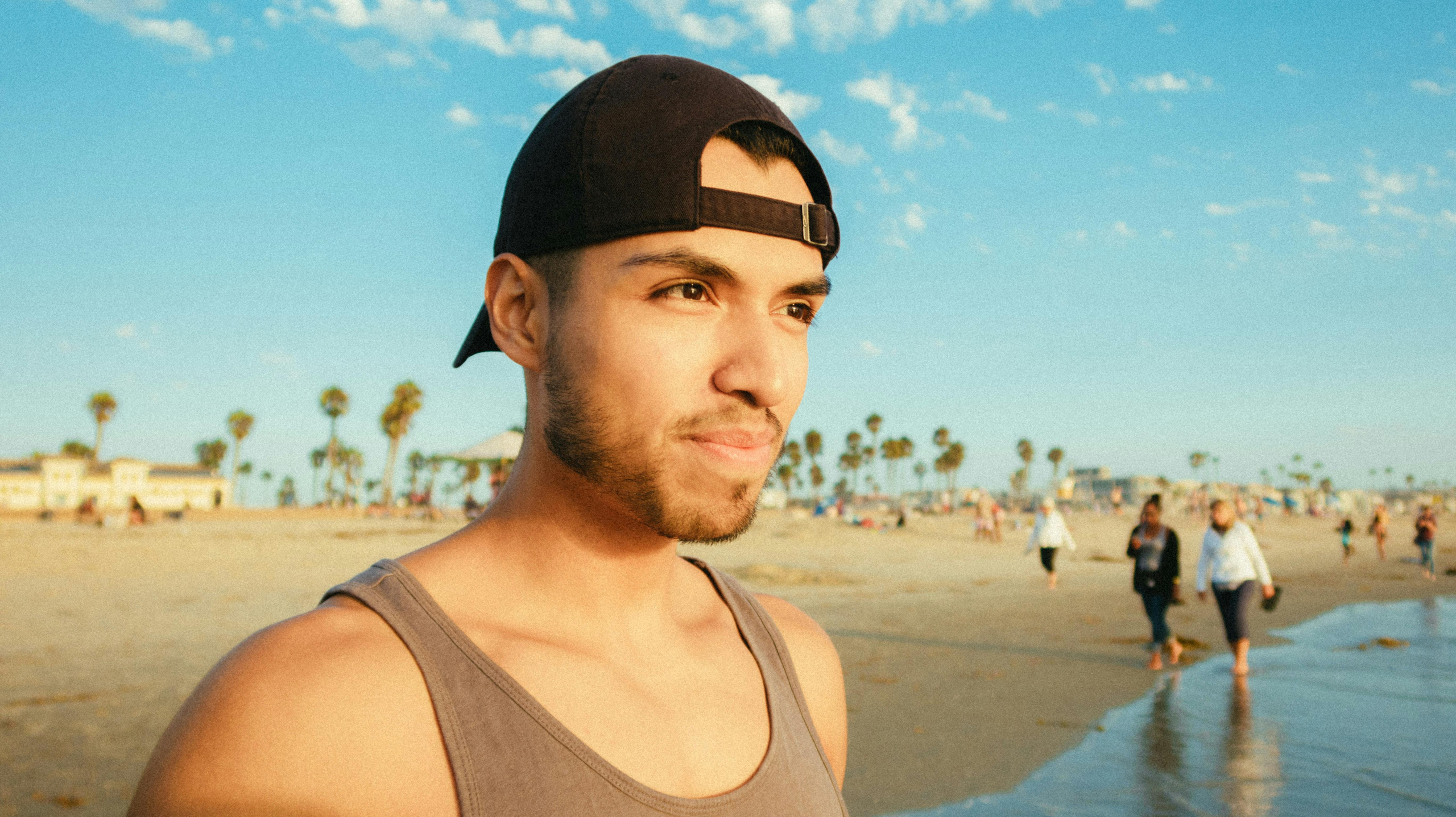 一个男人戴着帽子，在阳光明媚的海滩上，非常适合夏季休闲