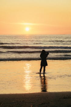 海边，剪影般的人物伫立在令人惊叹的日落余晖中