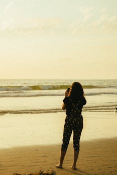 一名女子在海滩上欣赏日落，捕捉海浪的宁静