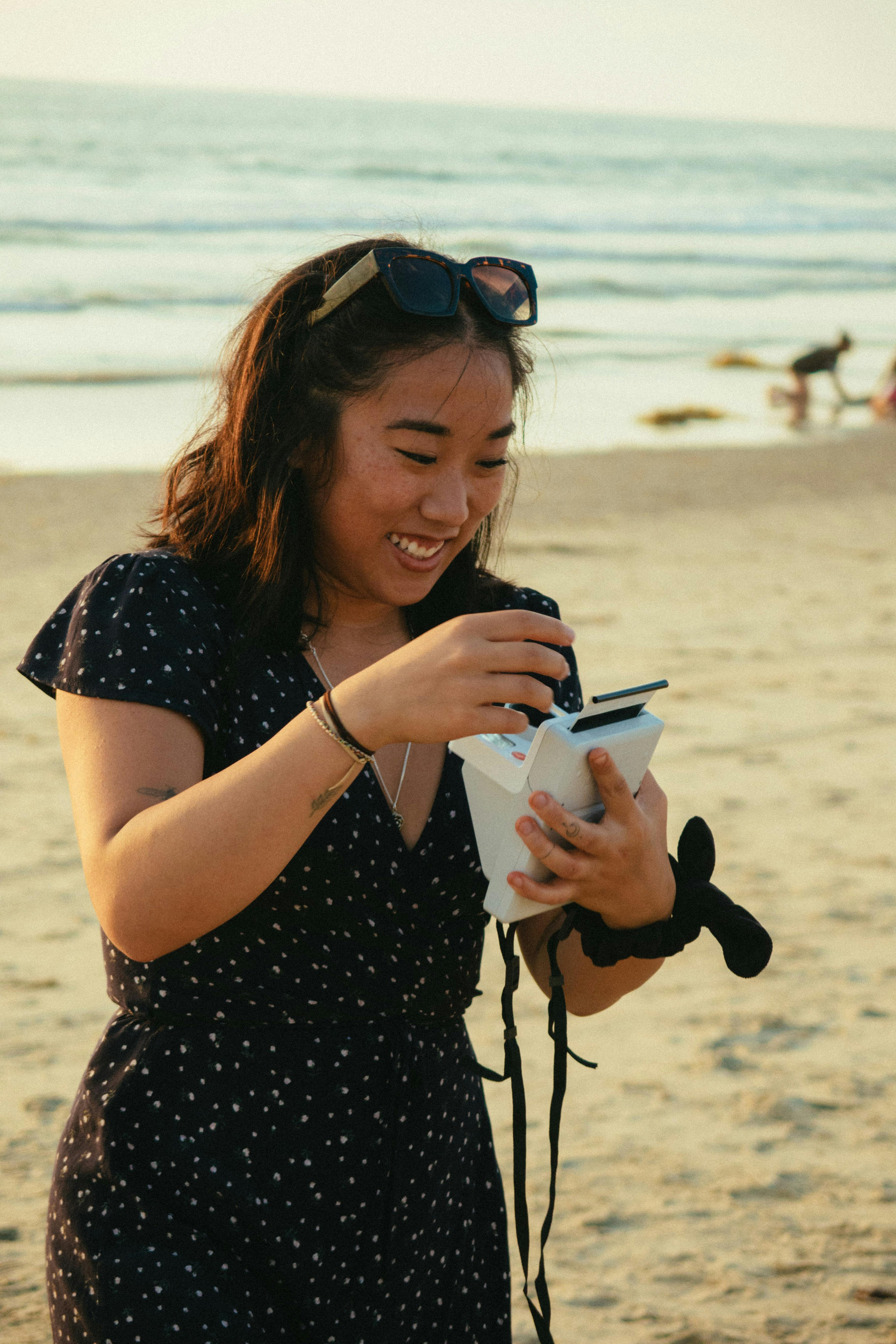 Happy woman with instant camera enjoying a sunny day at the beach.