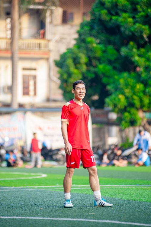 Free Young soccer player in red uniform smiling on a green field in Hanoi, Vietnam. Stock Photo