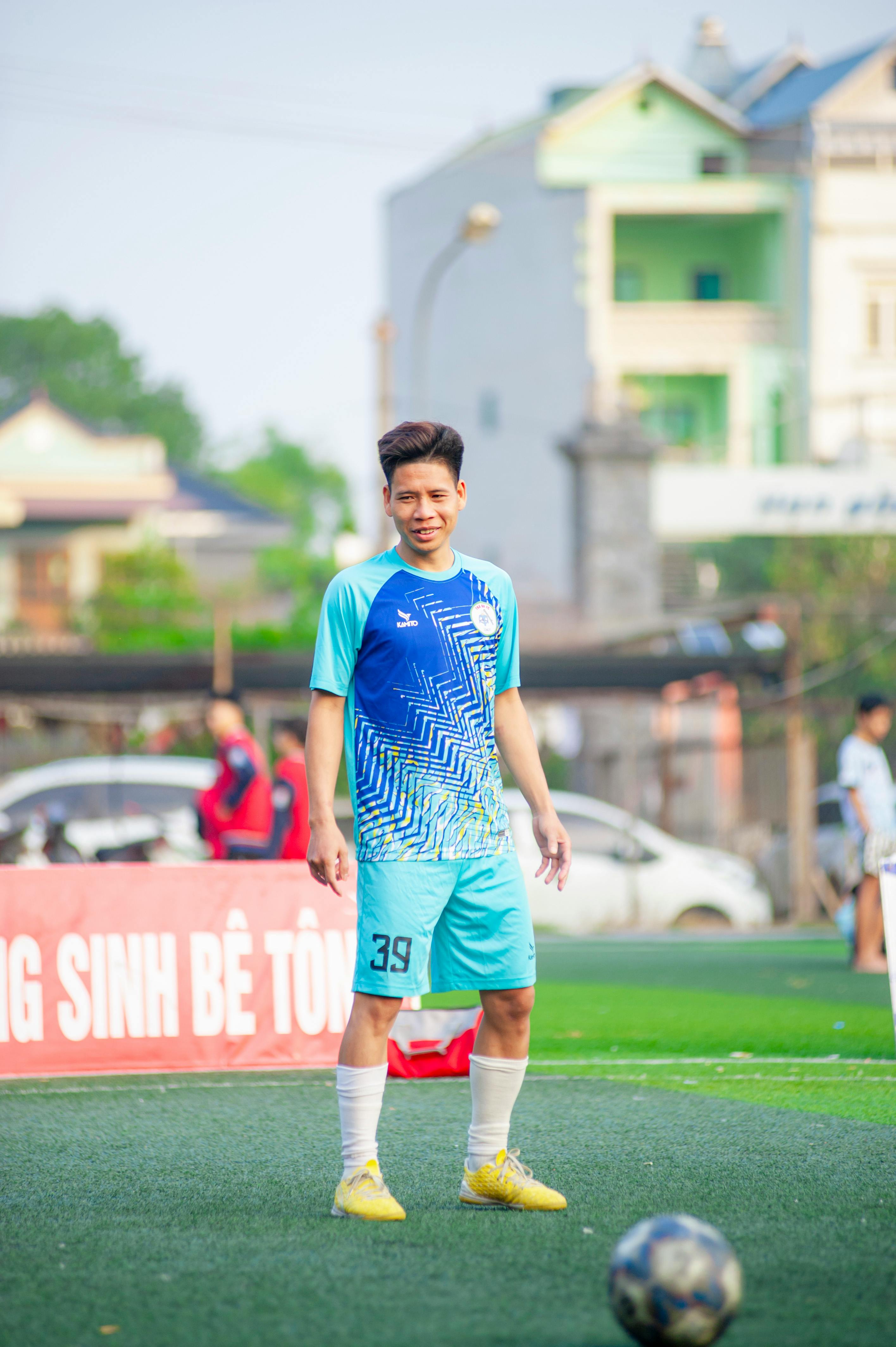 A young adult soccer player standing on a field in Hà Nội, Việt Nam.