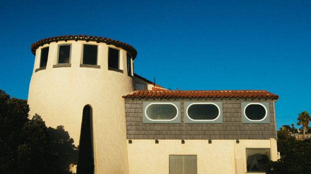 A striking residential building with round and rectangular windows under a vibrant blue sky.